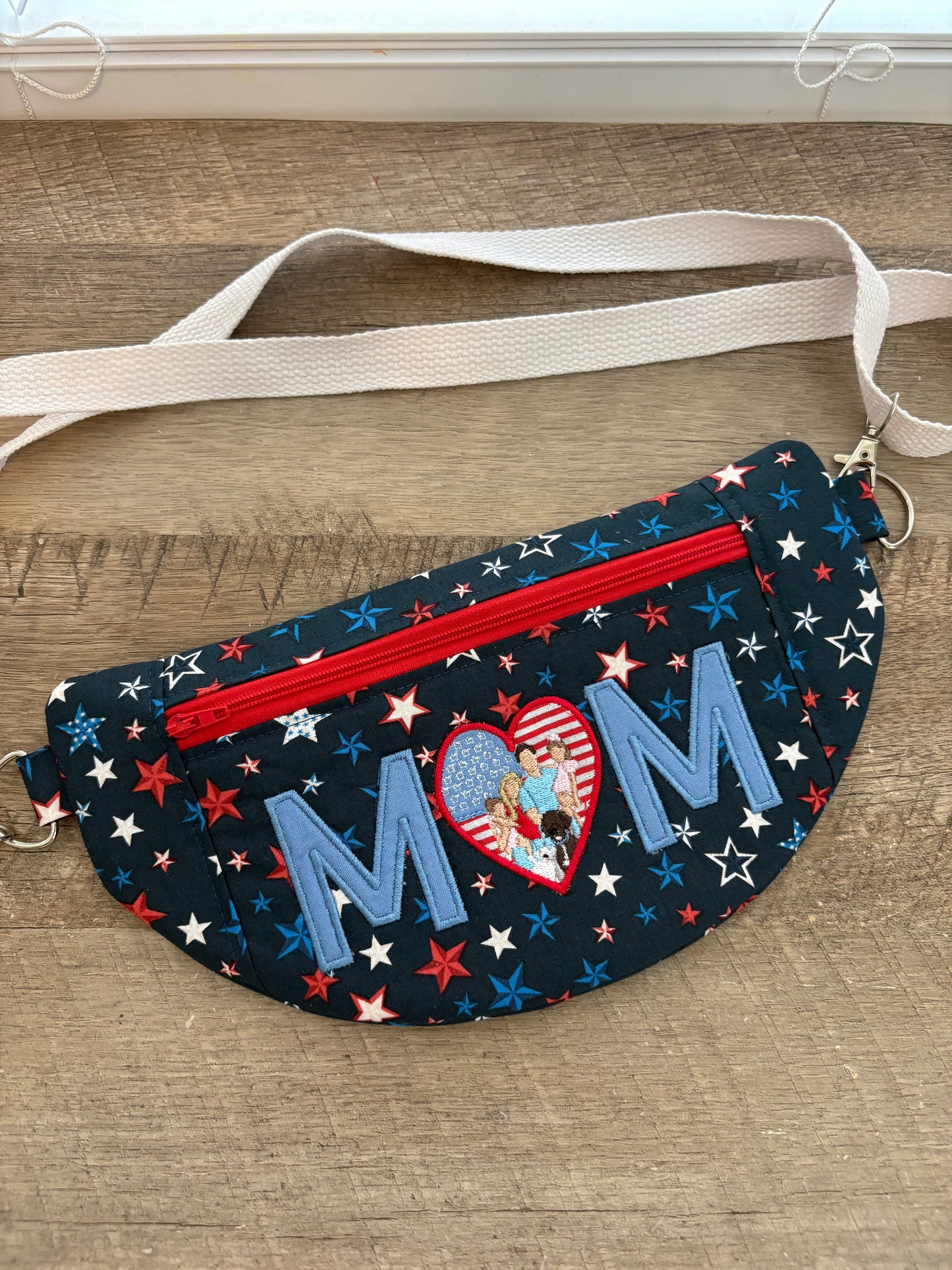 Crossbody bag with patriotic fabric and Mom embroidered across the front.