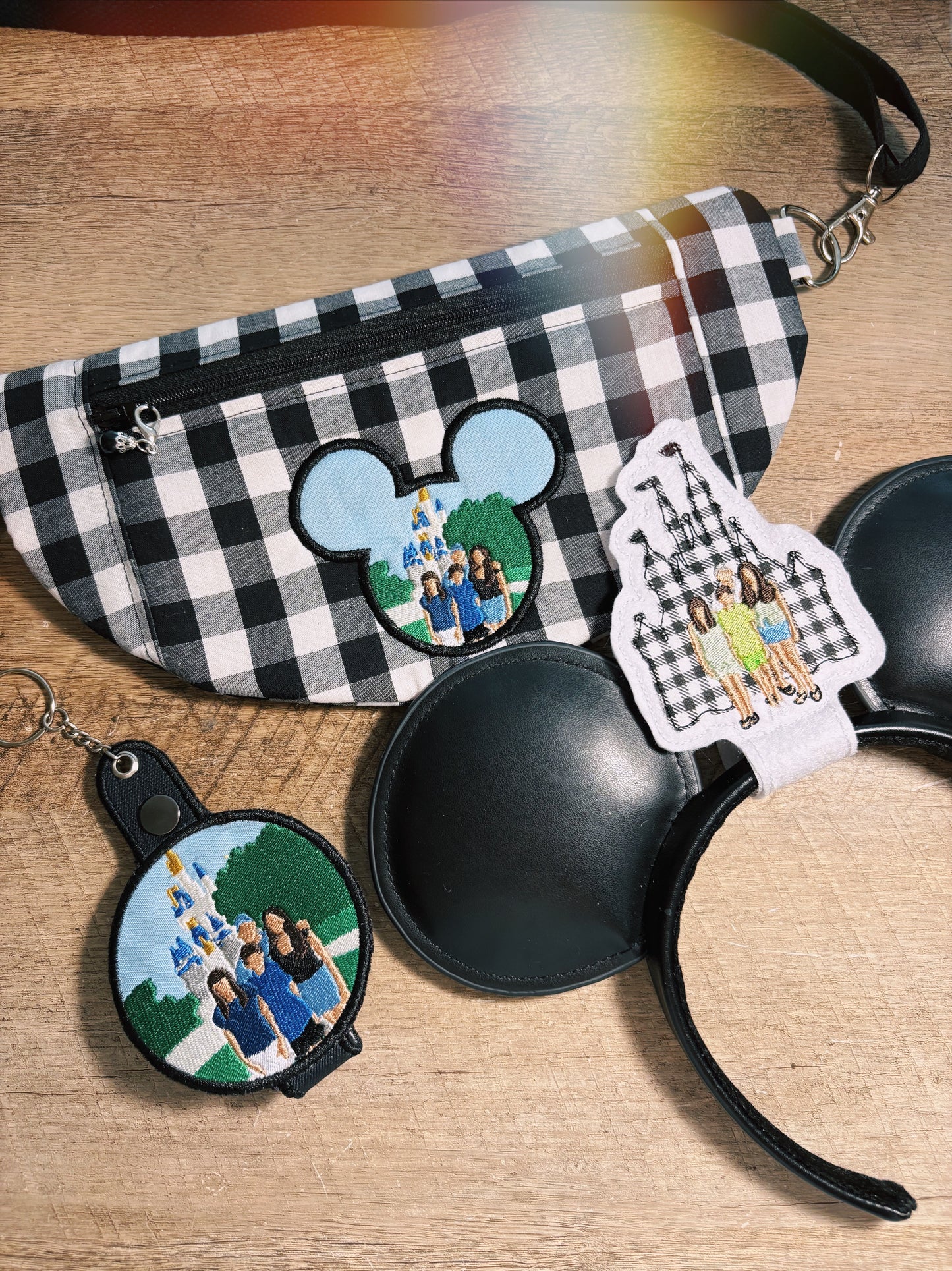 Black and white checkered pouch, black Minnie Mouse ears with photo charms, and keychain on a wooden surface.