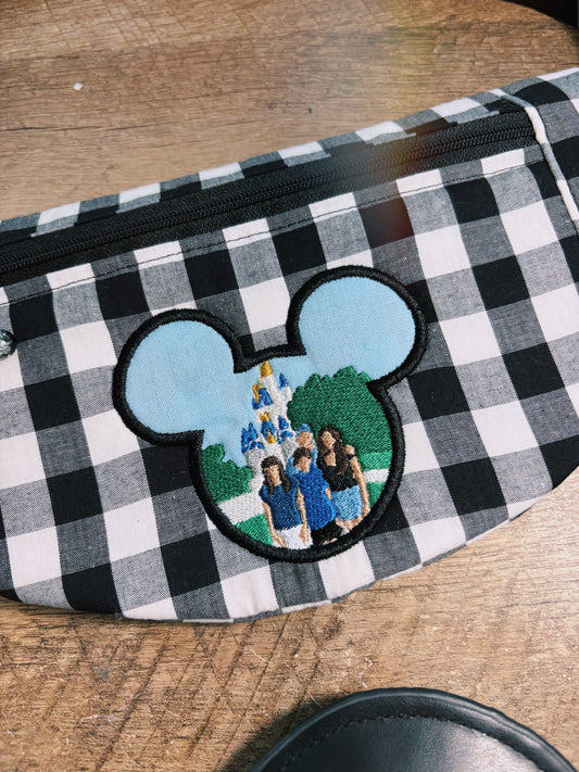 Checkered pouch with a patch of a family at a theme park on a wooden surface