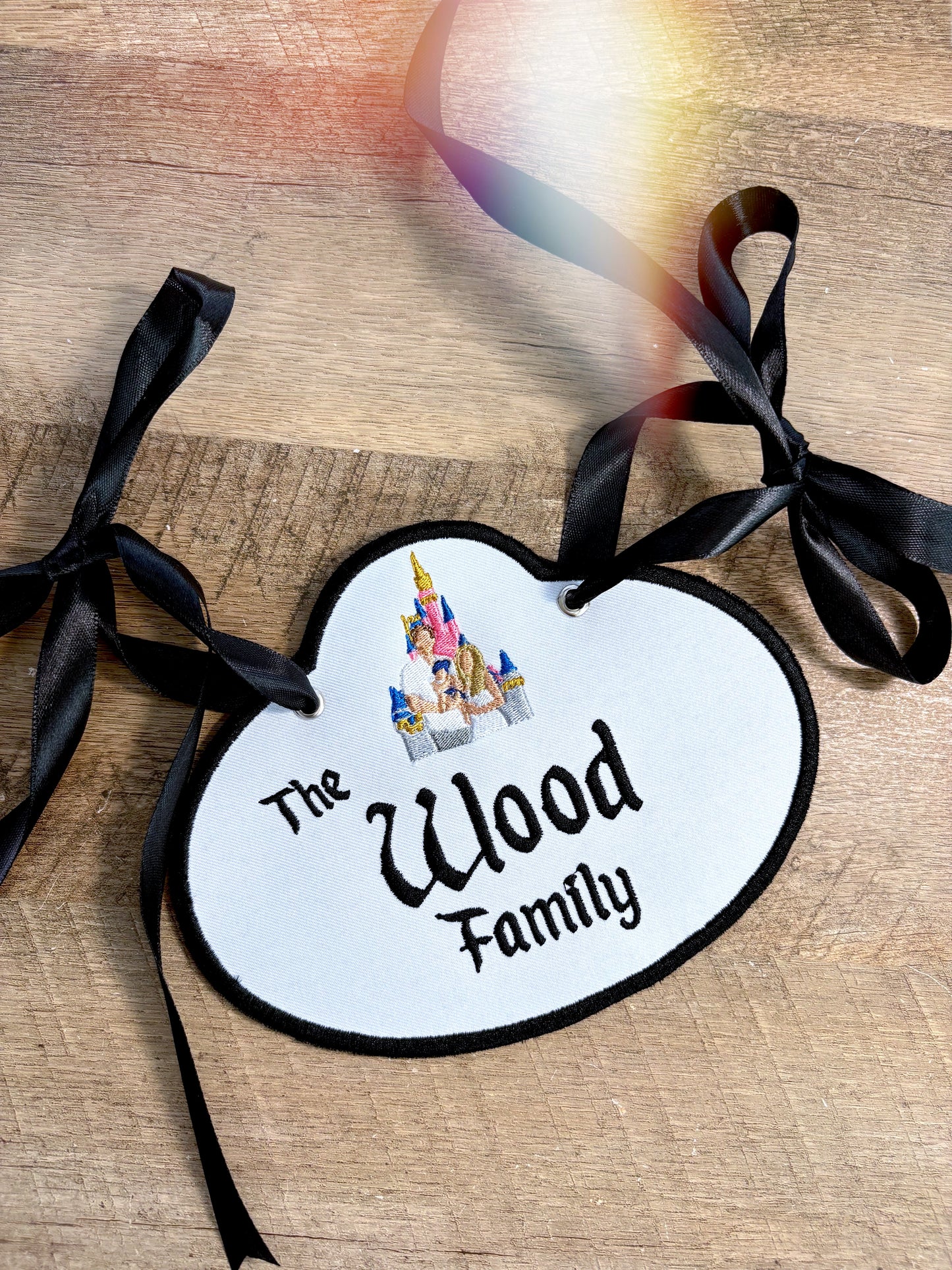 A stroller tag with embroidery that says “The Wood Family” with castle and a family.