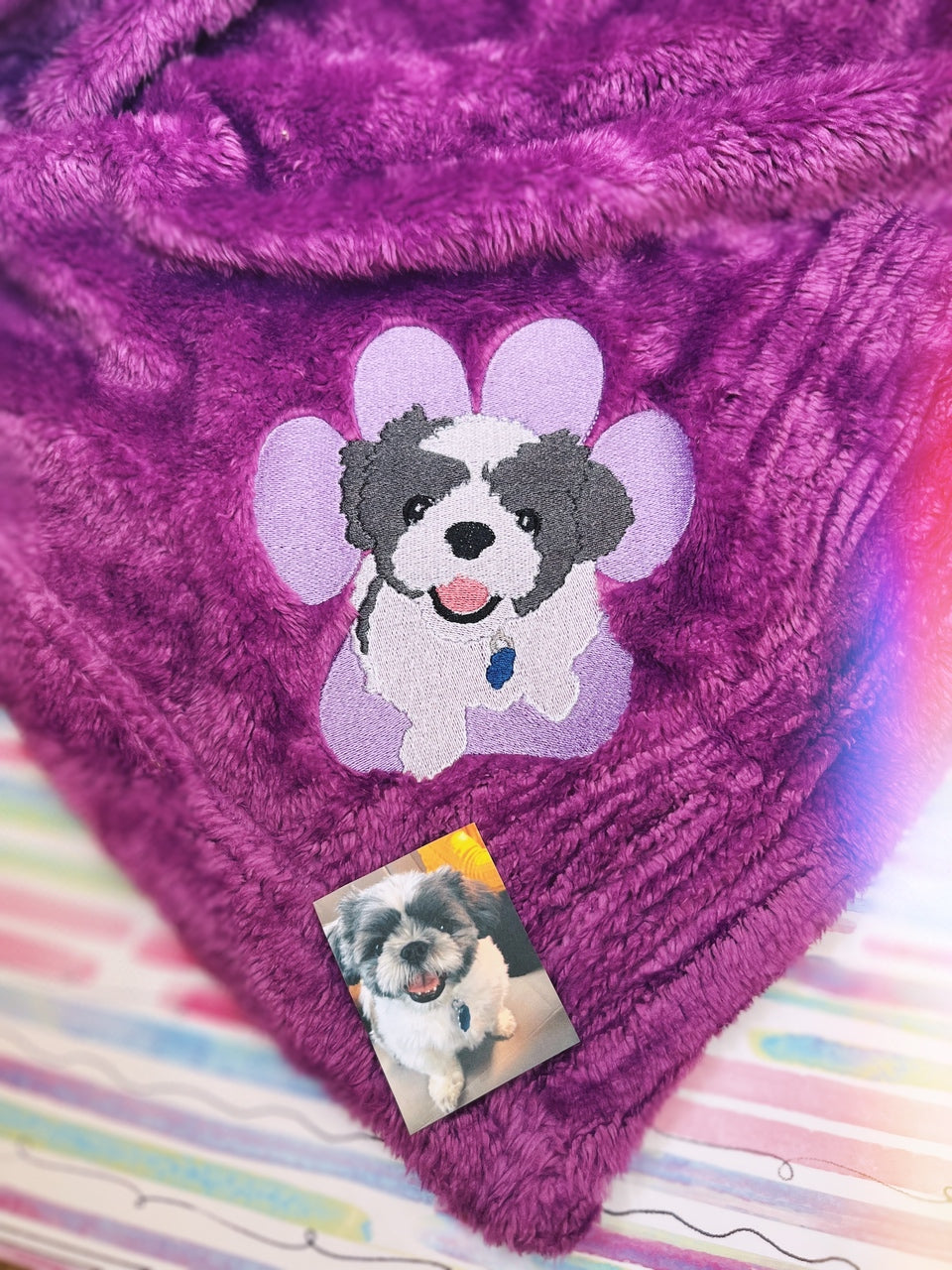 Purple blanket featuring embroidery of a pawprint and dog.