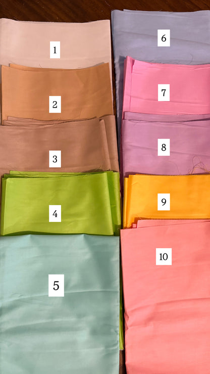 Folded fabric samples in various colors with numbers labeled on a wooden surface.
