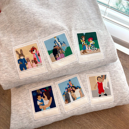 Two gray sweatshirts with retro film style embroidery of people and animals on a wooden surface.