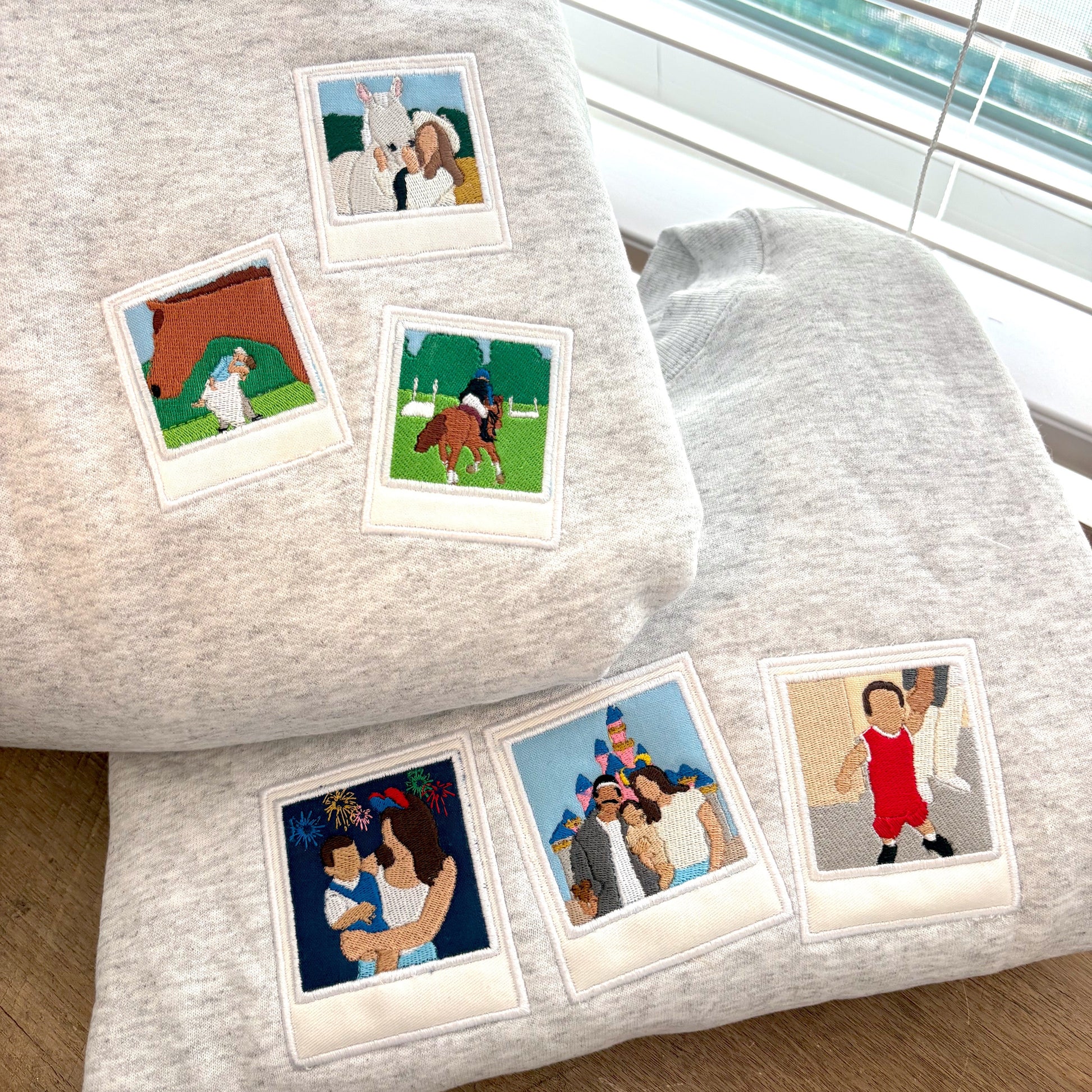 Sweatshirts with small retro film-style photos of people and animals on a wooden surface.