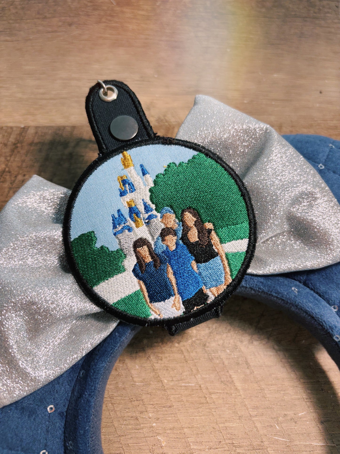 Embroidered keychain with a family portrait and castle design on a fabric background