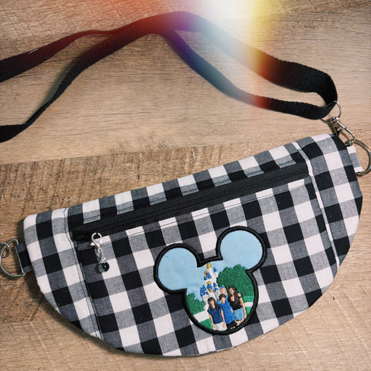 Black and white checkered fanny pack with a embroidered design on a wooden surface.