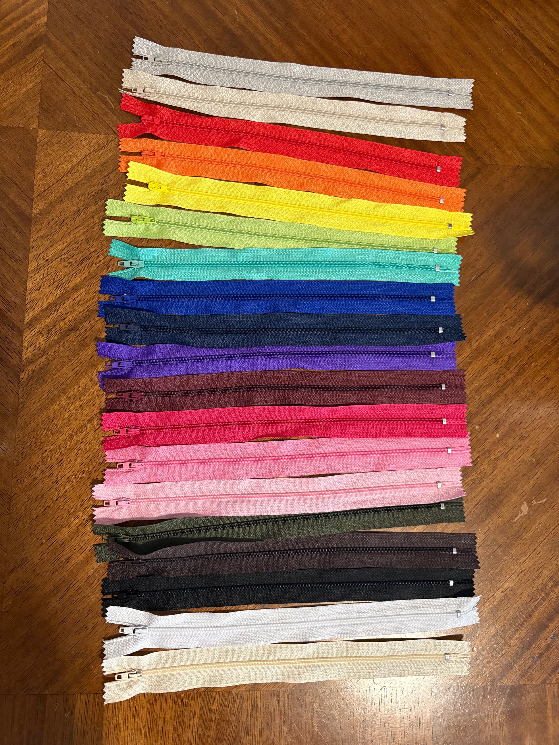Set of colorful zippers arranged in a grid on a wooden surface