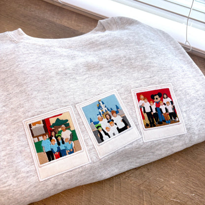 Gray sweatshirt with three retro film style embroidery of people on a wooden surface.