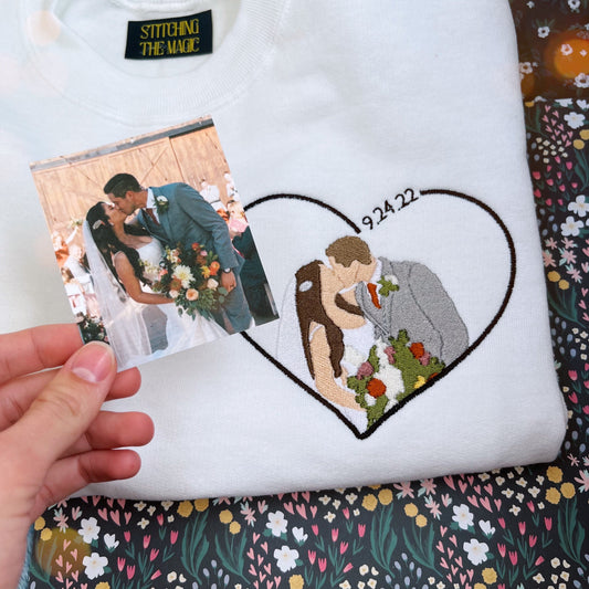 White sweatshirt with an embroidered couple on their wedding day surrounded with a heart. 