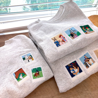 Wood background with three gray sweatshirts that all have retro photo style embroidery on them.