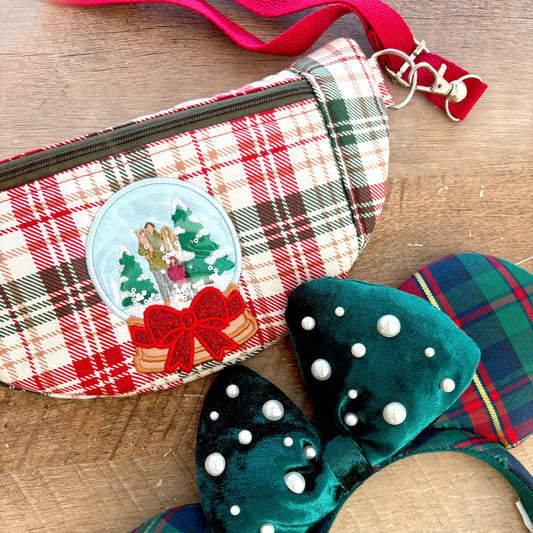 Crossbody bag with red and green plaid and an embroidered detail of a snow globe of a family.