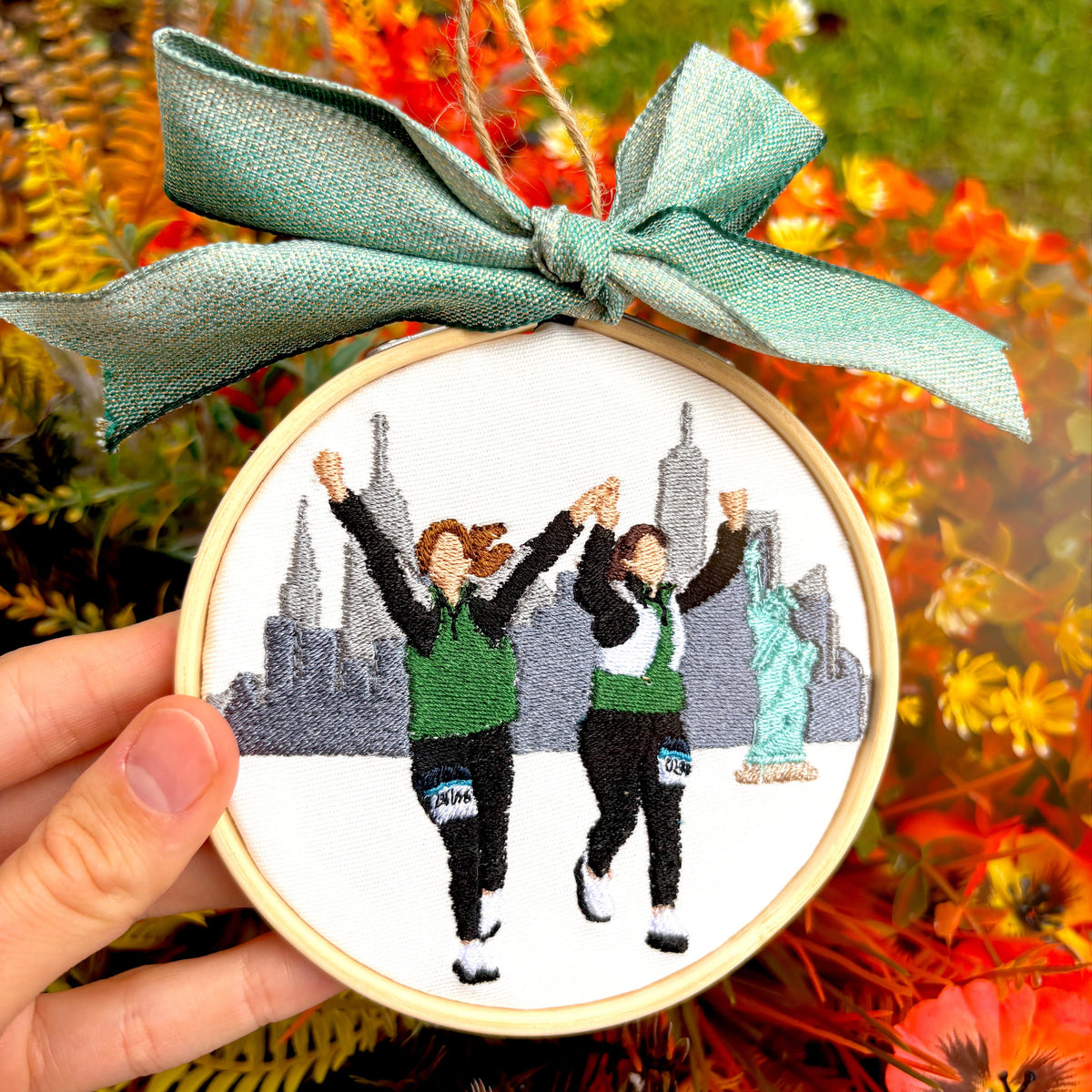 Fall floral background with a custom embroidered ornament of two girls running and a blue now on top.
