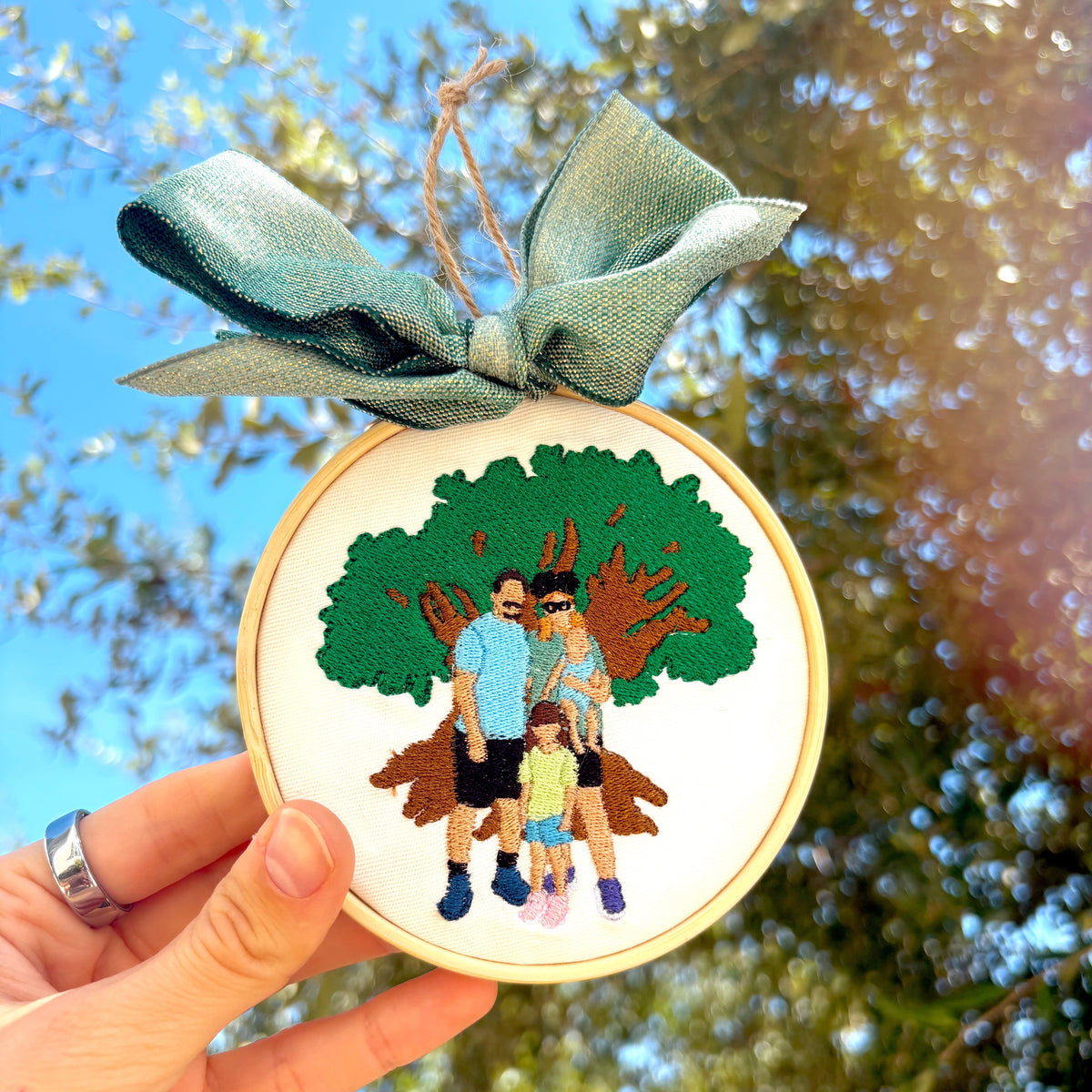 Tree background with a custom embroidered ornament in focus of a family and tree.